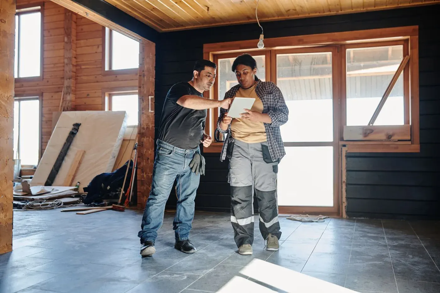 Deux professionnels de la construction consultent une tablette dans une maison en chantier
